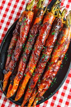 cooked carrots on a black plate with parsley and red checkered tablecloth