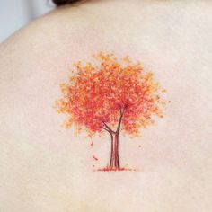 a woman's back with an orange tree tattoo on it