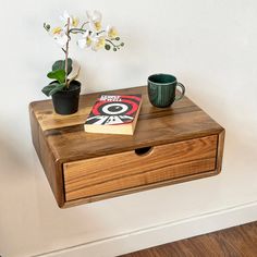 a wooden table with two cups and a book on it next to a flower pot