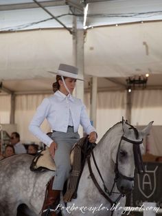 a woman riding on the back of a white horse