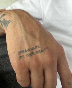 a man with a tattoo on his left hand and the words dream until it's your reality