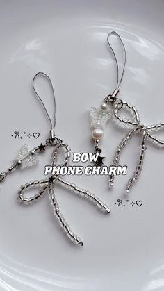 two pairs of earrings on a plate with the words bow phone charm