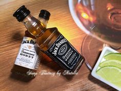 two bottles of jack daniels on a wooden table next to a bowl of limes