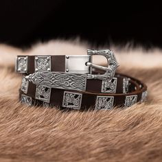 two brown leather bracelets sitting on top of a furry surface