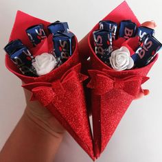 two red paper cones with candy bars wrapped in ribbon and decorated with white frosting