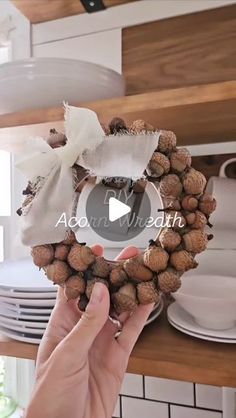 a person holding up a wreath made out of nuts