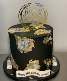 a black and gold birthday cake with money on top