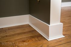 the corner of a room with wood flooring and white trim on the walls is shown