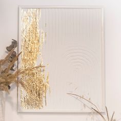 an abstract painting with gold paint on white paper next to dried plants and vases