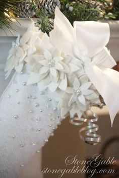 a christmas stocking hanging from a tree with white flowers and pearls on the bottom