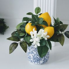 a blue and white vase filled with lemons and flowers