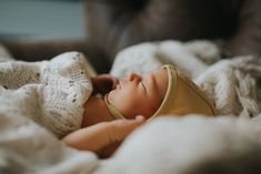 a newborn baby wrapped in a blanket on top of a bed