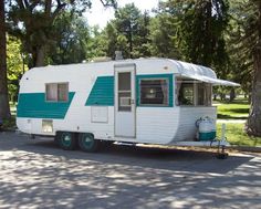 an rv parked on the side of the road in front of some trees and grass