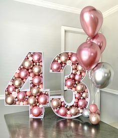 the number forty four is decorated with pink and silver balloons