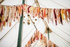 a chandelier hanging from the side of a white tent with colorful streamers