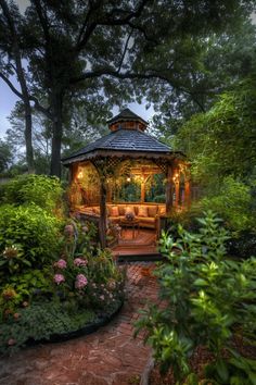 a gazebo surrounded by lush green trees and flowers