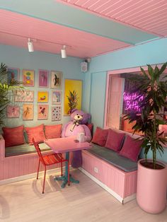 a living room with pink couches and pictures on the wall above it, along with a potted plant