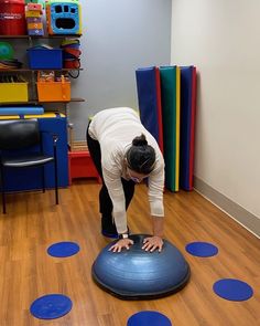 a woman is doing exercises on an exercise ball in the room with blue circles around her