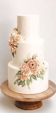 a three tiered cake with flowers painted on the side and wooden stand for display