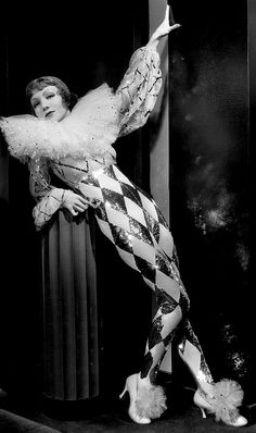 a woman dressed as a clown is posing for a photo in front of a column