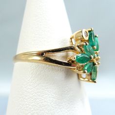 "IMPORTANT description is available following the details. Please, read on. Thank you. Material: 18K solid gold, natural brilliant cut diamonds, natural faceted navette emeralds Size: 5 3/4 size of the face of the ring 12mm x 12mm Weight: 2.5g Period: vintage Style: dinner, every day wear, birthday Provenance: an estate sale condition: very good (see description) Additional remarks: stamped with the owl marks plus the number 750 (inside the shank) N.b.: We guarantee the authenticity of our items Formal Green Marquise Emerald Ring, Marquise Emerald Ring For Formal Occasions In May, Formal Cluster Emerald Ring With Diamond Accents, Anniversary May Birthstone Emerald Ring With Single Cut Diamonds, Formal Emerald Cluster Ring For May Birthstone, Fine Jewelry Hallmarked Emerald Ring, Fine Jewelry Marquise Emerald Ring With 17 Jewels, Hallmarked Emerald Diamond Ring For May Birthstone, Fine Jewelry Marquise Cut Emerald Ring With Diamond Accents