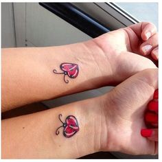 two girls with matching tattoos on their arms and wrist, both have hearts in them