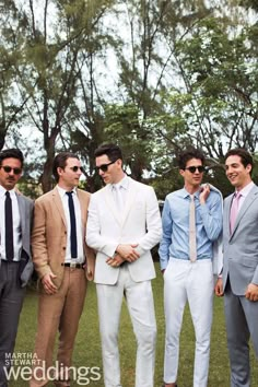 a group of men standing next to each other in front of trees wearing suits and ties