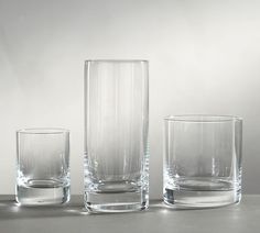 three clear glass vases sitting on top of a gray table next to each other