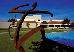 a large metal sculpture in the middle of a lawn next to a blue swimming pool