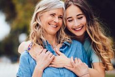 two women are hugging each other outside