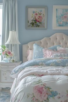 a bedroom with blue walls and pink flowers on the bedspread, two framed pictures above the bed