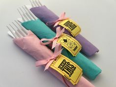 there are four different colored napkins on the fork holders with ribbons tied around them