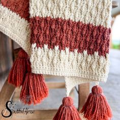 a crocheted blanket with tassels hanging from it