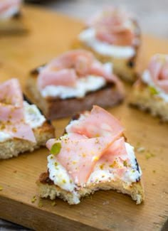 several pieces of bread with various toppings on them sitting on a wooden cutting board