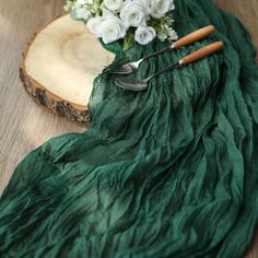 a green table cloth with flowers and utensils on it next to a wooden slice