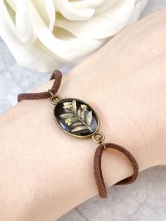 a woman's arm with a bracelet on it and a white rose in the background