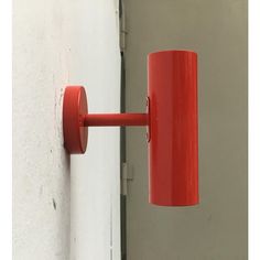 a red light hanging from the side of a white wall next to a gray door