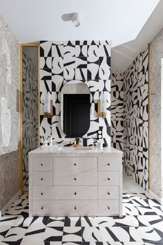 a bathroom with black and white wallpaper, gold trimmings and a large mirror