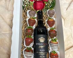 a bottle of wine and some strawberries in a box with flowers on the side