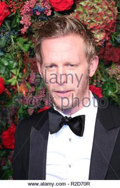 a man in a tuxedo and bow tie posing for the camera