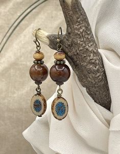 Handmade, unique boho style ceramic earrings. Brown, tan and blue in color. A nice size length at 2-1/8 inches long by .50 inch wide. The round, brown bead is glazed ceramic with a complimenting Czech glass bead at the top. From the bottom hangs a kiwi style Picasso Czech glass bead in blue and tan with a brown Picasso edge. Paired with bronze wires, hooks, and accent beads, these make a perfect casual, rustic style for everyday. They would be great for fall with a sweater and jeans. Give them a Bohemian Brown Beaded Nickel-free Earrings, Bohemian Brown Earrings As Gift, Bohemian Brown Earrings For Gift, Bohemian Brown Beaded Round Earrings, Bohemian Brown Round Earrings, Brown Bohemian Round Earrings, Bohemian Brown Beaded Earrings For Gift, Nickel-free Beige Bohemian Jewelry, Bohemian Nickel-free Beige Jewelry