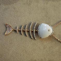 A unique fish-bone pendant featuring a piece of white onyx as the head and 1.00 carats of round brilliant cut diamonds set along the “bones” of the deceased fish. Each of the 18k rose gold bones are attached by independent links allowing them to be folded and move with ease. A fun piece in 18k rose gold, the pendant comes with a 18k gold chain.    Pendant Length: 2 inches    Chain Length: 18 inches Fish Bone Necklace, Gold Chain Pendant, Unique Fish, Fish Jewelry, 18k Gold Chain, White Onyx, Bone Pendant, Vintage Beads Necklace, Peridot Necklace