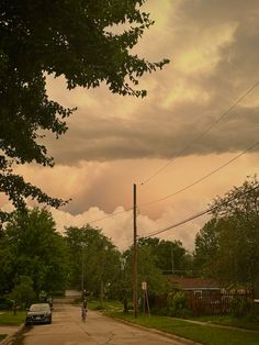 a street with cars parked on the side of it and clouds in the sky above