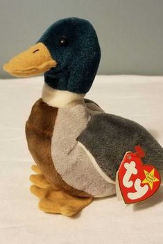 a stuffed duck with a tag on it's head sitting on a white surface