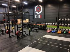 an indoor gym with rows of weight benches and barbells in front of the wall