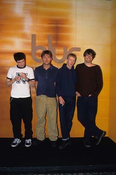 four young men standing in front of a yellow wall