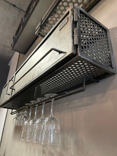 wine glasses are lined up on the wall next to a metal shelf that holds four wine glasses