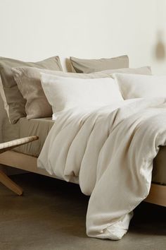 an unmade bed with white sheets and pillows