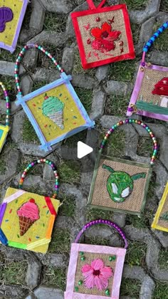 several handmade bags with designs on them sitting on the ground next to some rocks