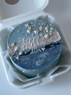 a blue birthday cake with white frosting and sprinkles in a box